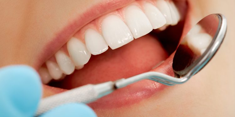 Close-up of patients open mouth during oral checkup with mirror near by